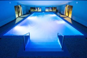 a large swimming pool with blue lighting in a building at Pensiunea Art 1000 in Lunca Vişagului