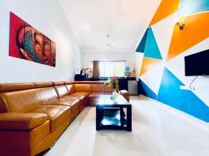 a living room with a brown couch and a table at Stunning 4bhk Pool View Apartment 2bhkX2 in Vagator