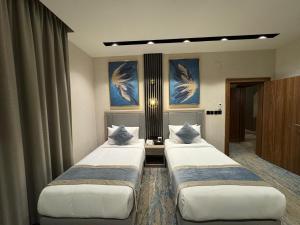 2 camas en una habitación con pinturas en la pared en Niyama Hotel, en Umm Lajj