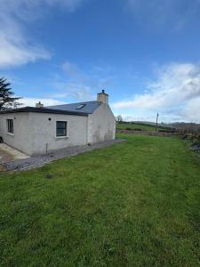 ein weißes Haus mit einem Grasfeld davor in der Unterkunft Patsys Cottage in Ballyshannon