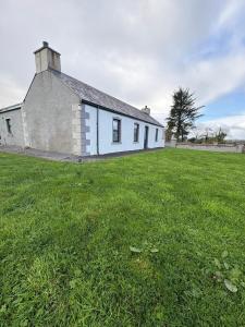 ein Gebäude mit einem Grasfeld davor in der Unterkunft Patsys Cottage in Ballyshannon