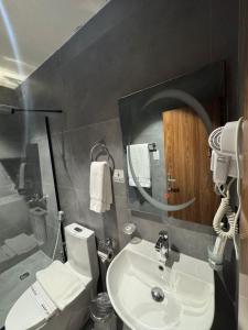 Un baño con lavabo, inodoro y espejo. en Niyama Hotel, en Umm Lajj