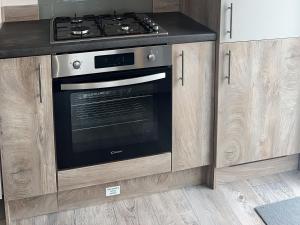 a stove in a kitchen with wooden cabinets at 30 Wells Close in Cheswick +11 photos