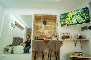 een vrouw zittend op een bed in een kamer met twee stoelen bij Daria’s home apartament in Palermo