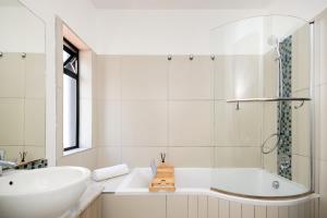 a white bathroom with a tub and a sink at The Atrium, Sandton Apartment in Johannesburg +23 photos