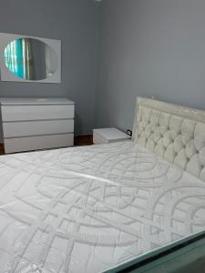 a bedroom with a white bed and a dresser at Amber Comfort Home in Lushnjë