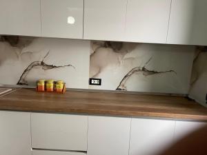 a kitchen with white cabinets and a counter with canisters on it at Amber Comfort Home in Lushnjë