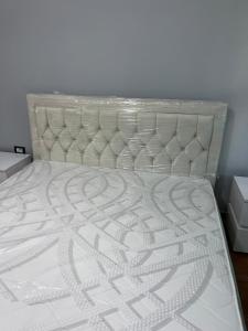 a bedroom with a white bed with a white headboard at Amber Comfort Home in Lushnjë