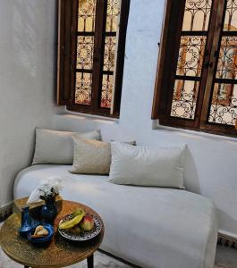 un sofá con una mesa con un bol de fruta. en Riad Dar Lghizlane, en Marrakech
