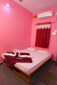 a pink room with a bed with a red curtain at kali river view in Dandeli