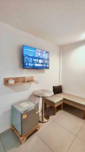 Una sala de espera con una mesa, un banco y un televisor en P2 by Passion : พีทู รีสอร์ต วังรัก, en Nakhon Si Thammarat