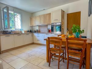 een keuken met een tafel en stoelen en een keuken met witte kasten bij Charming house in Oppede - Swimming Pool & Tranquility in Oppède