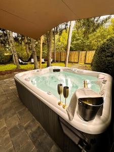 eine Badewanne mit Waschbecken und zwei Weingläsern in der Unterkunft Wellness Tuin - Ultieme Partner Beleving - Privé Wellness Vakantiehuis met Privé Jacuzzi in Privé tuin, Privé Indoor Sauna en Privé Indoor Stoomcabine in Koloniale Stijl - Gratis Fles Prosecco & Leuke Partner Connect Box ! in Horst