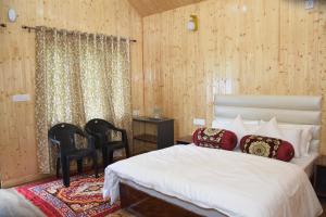 a bedroom with a white bed and two chairs at Shivanchal Homestay & Cottage in Uttarkāshi