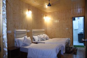 a bedroom with two beds with white sheets and pillows at Shivanchal Homestay & Cottage in Uttarkāshi