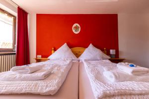 two beds in a bedroom with a red wall at Goldiger Hirsch Pension mit Gemeinschaftsküche in Immenstadt im Allgäu