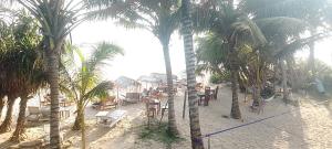 a beach with palm trees and tables and chairs at Kusuma's Lazy Left hostel in Midigama