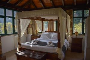 a bedroom with a canopy bed in a room with windows at Muntenia Inn Apartments and Suites in Kalavrita