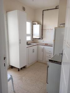 a kitchen with white cabinets and white appliances at Dar selma in Port El Kantaoui