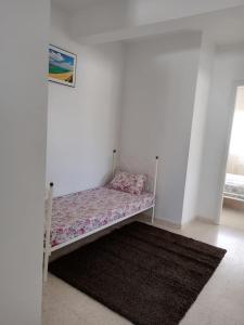 a small bed in a white room with a rug at Dar selma in Port El Kantaoui