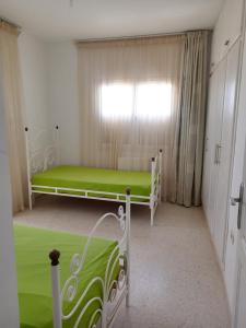 a bedroom with a green bed and a window at Dar selma in Port El Kantaoui