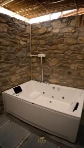 een badkuip in een kamer met een stenen muur bij Elan Luxuria Jawai in Bijāpur