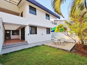 a white house with a patio and a table with an umbrella at ll EMPYREAN STAY ll MARIGOLD VILLA ll 3BHK ll AC ll PRIVATE POOL ll in Lonavala