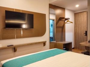 a bedroom with a bed and a tv on the wall at Front One Luxe Hotel Solo in Solo