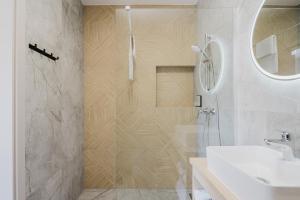 a white bathroom with a shower and a sink at S1 Apartamenty in Rewa