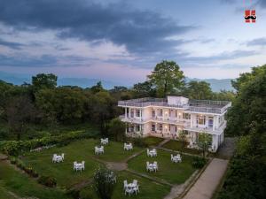 a large white house with white horses in the yard at Moustache Bir in Bīr