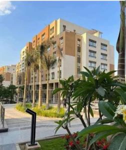 a building with palm trees in front of a street at cozy flat in New Administrative Capital near European universities in Kafr ash Sharā‘inah