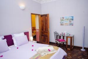 a bedroom with a bed and a table with a chair at Maison Lovasoa in Antananarivo