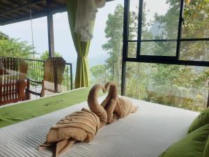 two towel animals sitting on a bed in front of a window at Ella Mount Relax Cottage in Ella