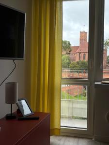 马尔堡Widok na Zamek的客房设有带黄色窗帘的大窗户。 更多10张照片