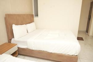 バンガロールにあるHotel Luma Suites-Cottonpetの白いシーツが敷かれた大きなベッドのある寝室