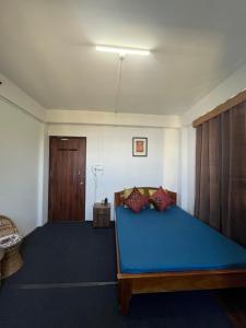 Un dormitorio con una cama azul y una puerta en Degants pad, en Darjeeling