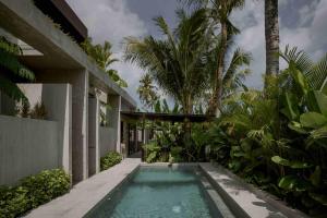 een zwembad voor een huis met palmbomen bij Tibah in Tanah Lot