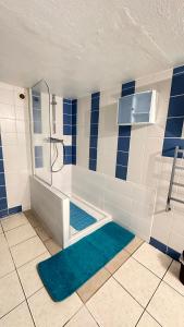 a blue and white bathroom with a tub and a shower at La Souste appartement avec jardin privatif in La Fare-en-Champsaur