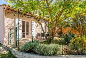 ein Haus mit einem Zaun vor einem Baum in der Unterkunft logement indépendant avec jardinet in Bouc-Bel-Air