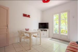 ein Wohnzimmer mit Tisch und Stühlen und einem Fernseher in der Unterkunft logement indépendant avec jardinet in Bouc-Bel-Air