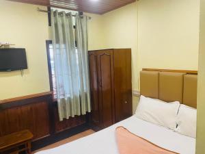 a bedroom with a bed and a tv and a window at ooty-mystique inn in Ooty
