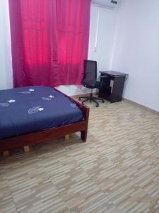 een slaapkamer met een bed, een bureau en een stoel bij Chambre et Salon in Agboogba