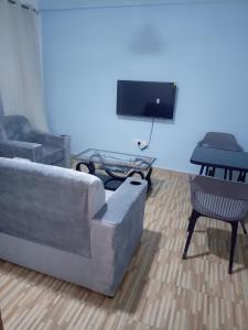 een woonkamer met een bank, een tafel en een tv bij Chambre et Salon in Agboogba