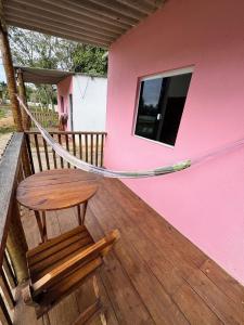 a chair on a porch with a pink wall at Suítes Ohana in Peruíbe