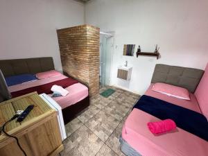 a room with two beds and a brick wall at Suítes Ohana in Peruíbe