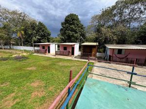 a house with a fence in front of a field at Suítes Ohana in Peruíbe