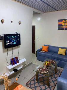 a living room with a blue couch and a tv at LES LOGIS DE NOUVELLE ROUTE BASTOS in Yaoundé