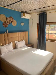 a large bed in a room with a blue wall at LES LOGIS DE NOUVELLE ROUTE BASTOS in Yaoundé