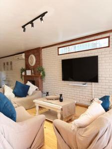 Una sala de estar con sofás y un televisor de pantalla plana. en Nimara de So, en Gordonʼs Bay 20 fotos más