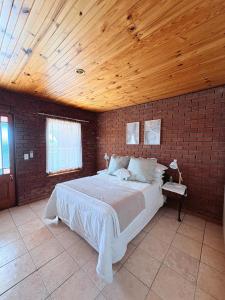 Un dormitorio con una cama grande en una pared de ladrillo. en Nimara de So, en Gordonʼs Bay